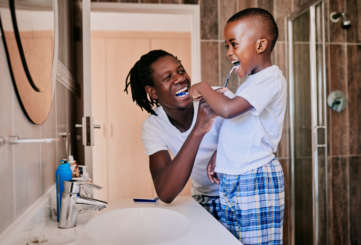 A father and son brush their teeth at home