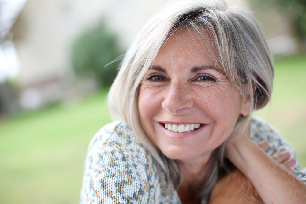 A close up image of a smiling senior woman with beautiful teeth and styled hair