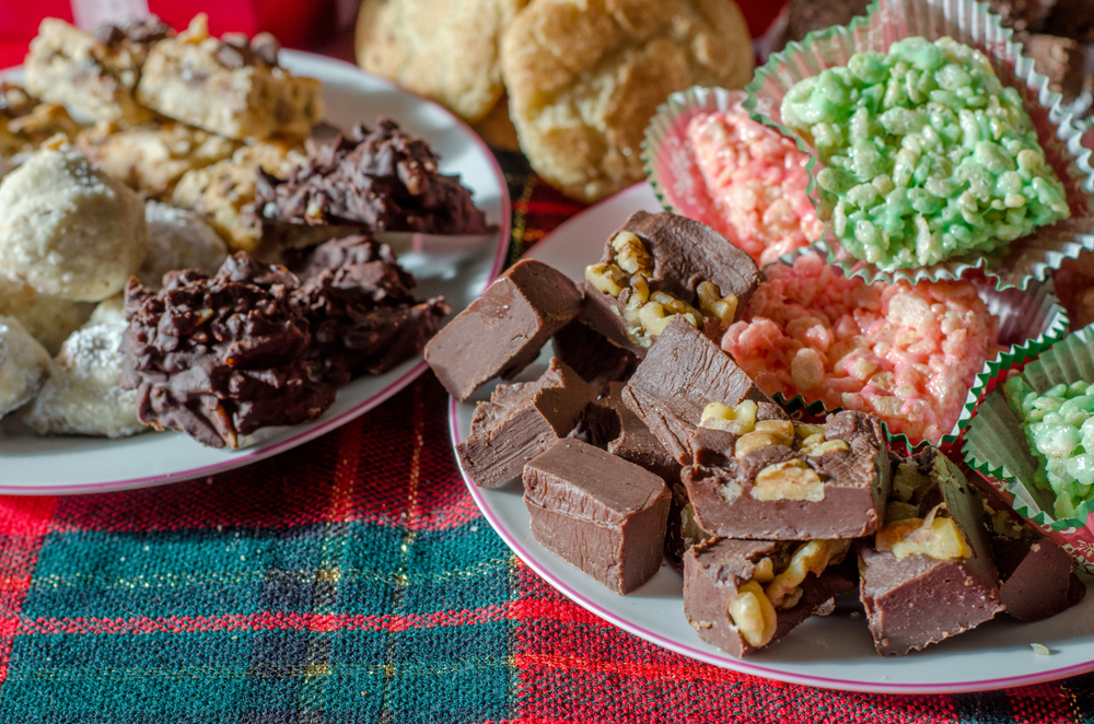 A close up of a dining table with two plates full of many different kinds of holiday baked goods